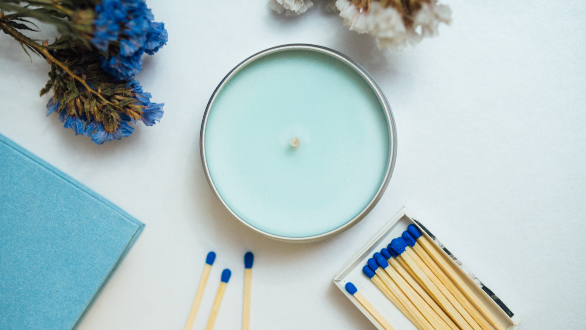 Blaue Kerze im Glas mit blauen Blumen und blauen Streichhölzern von Feierwerk